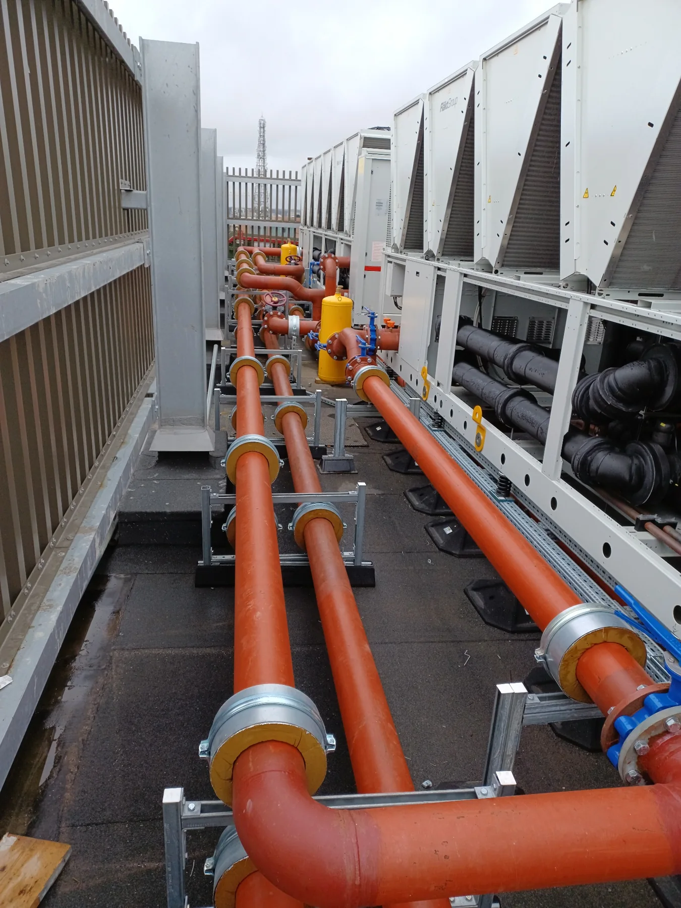 External cooling plant with large insulated and painted pipework, pipe supports and air-cooled equipment