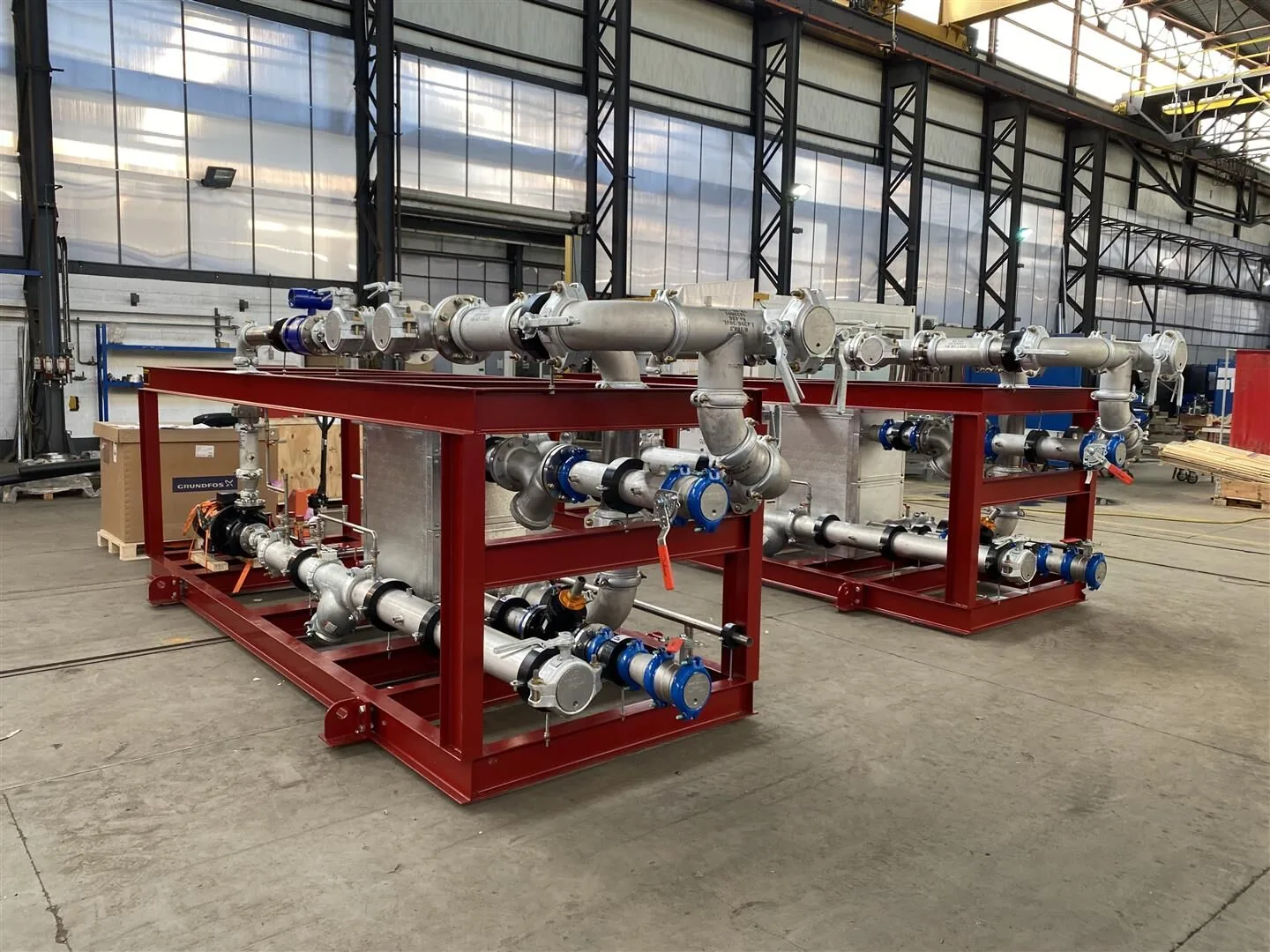 Prefabricated mechanical skids with steel support frames, pumps, valves and pipework in a workshop