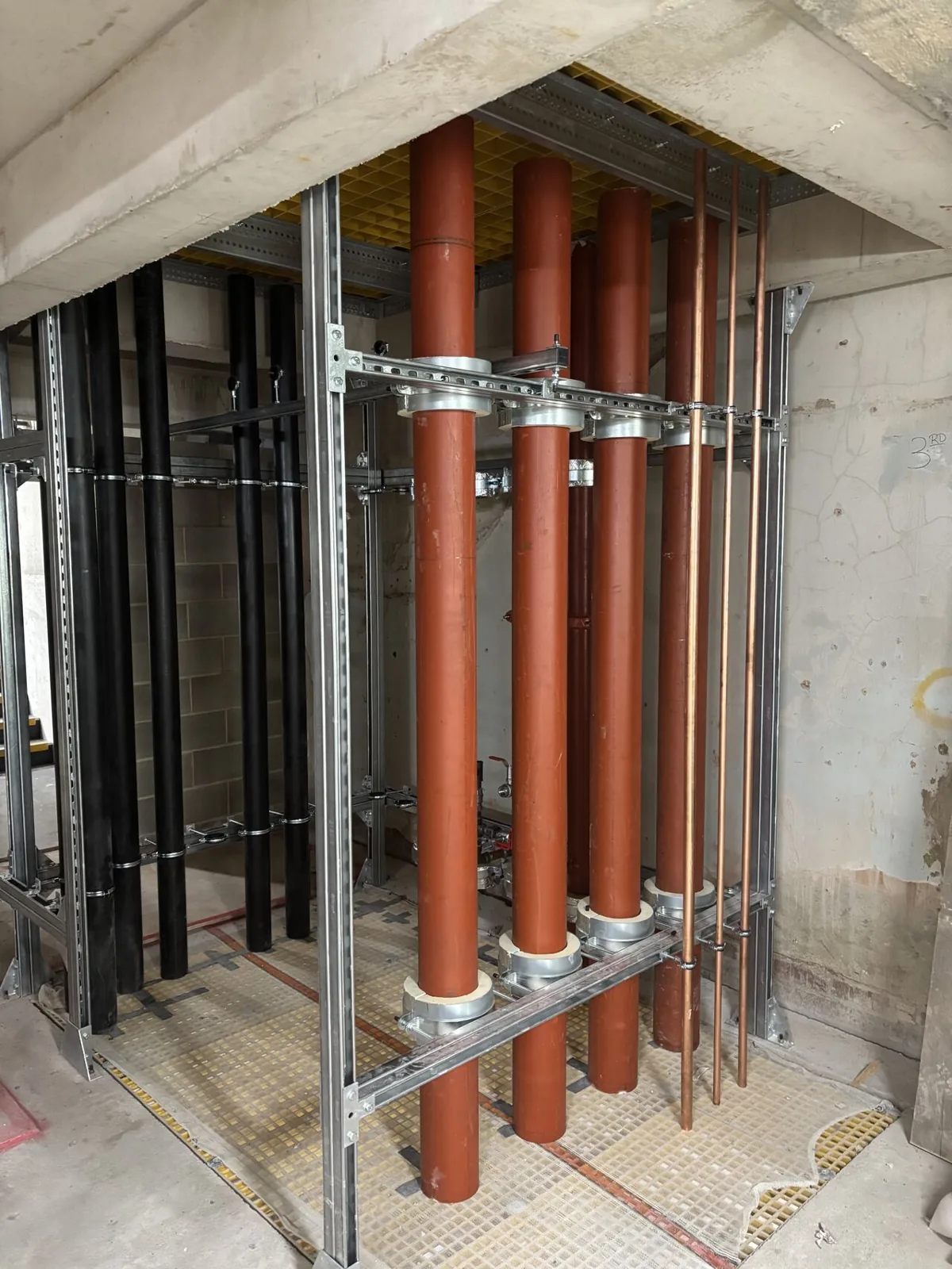 Vertical mechanical services riser with pipework and galvanised steel support framing